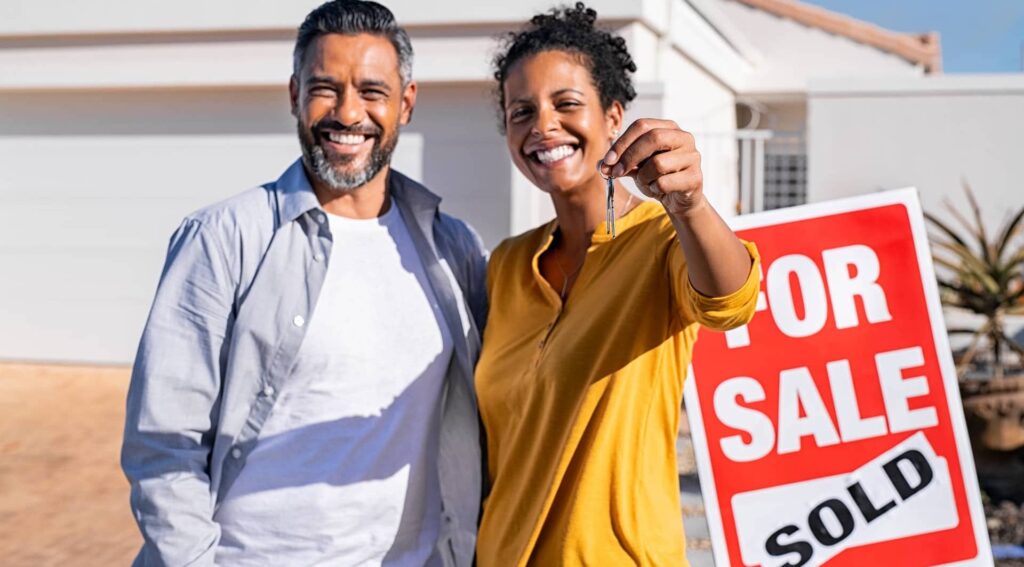 Couple In Front of For Sale:Sold Sign