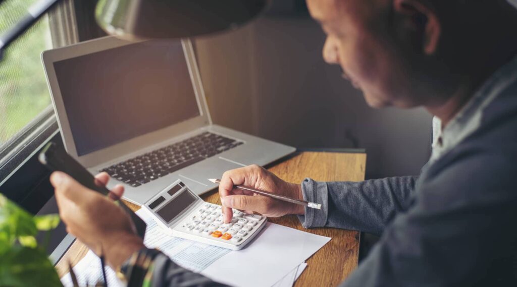 Man Typing on Calculator Doing Taxes