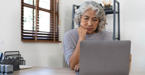 Elderly Woman Looking at Laptop at Desk