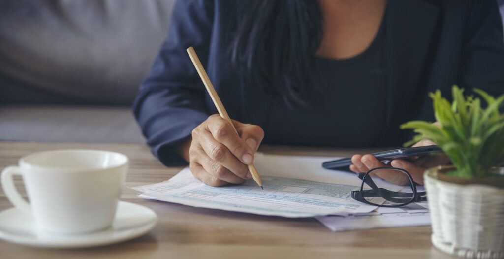 Person with Calculator and Pencil Reviewing Paper
