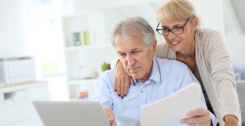 Couple Looking at Their Computer and Reviewing Paperwork